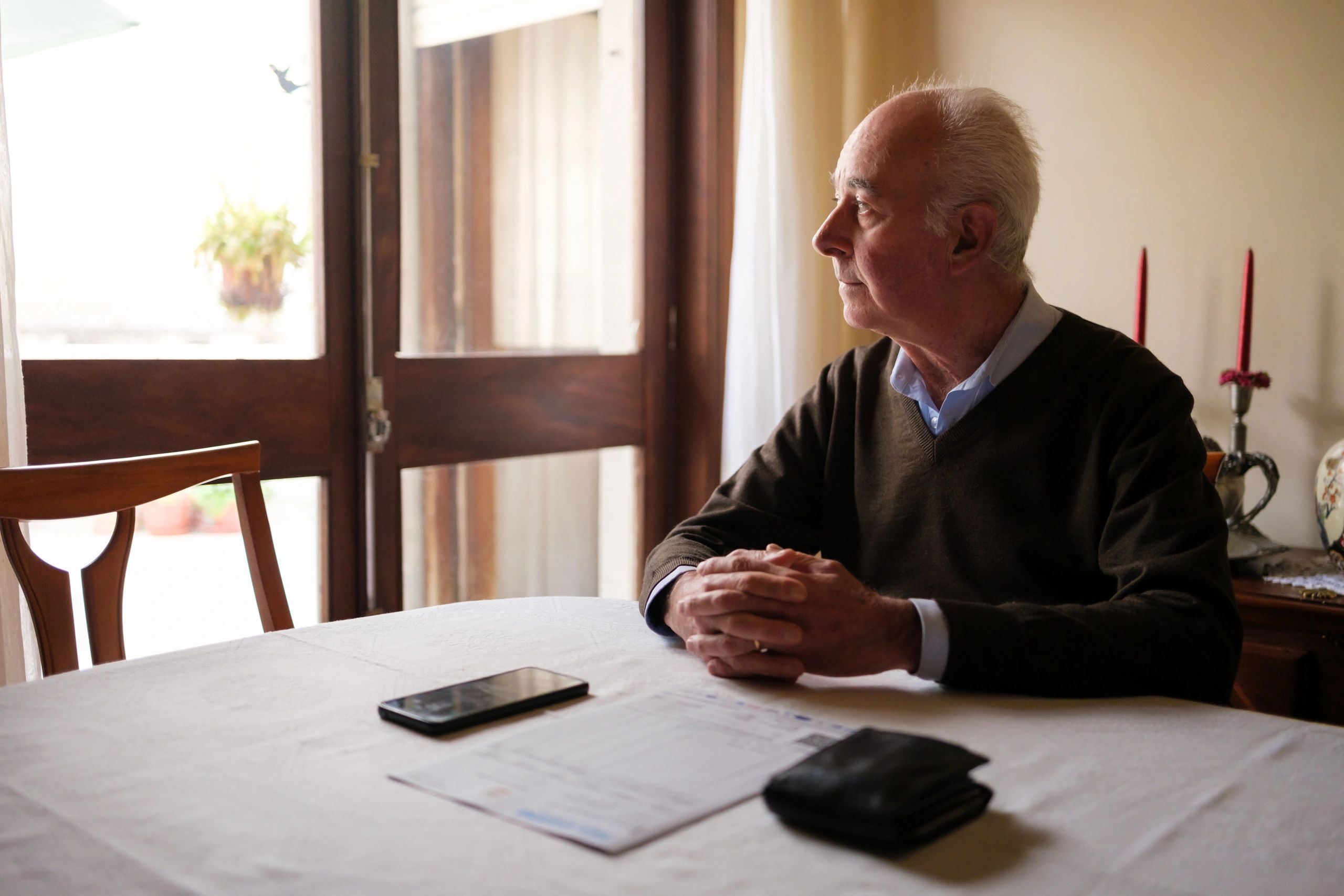 Senior man sitting at table looking through window